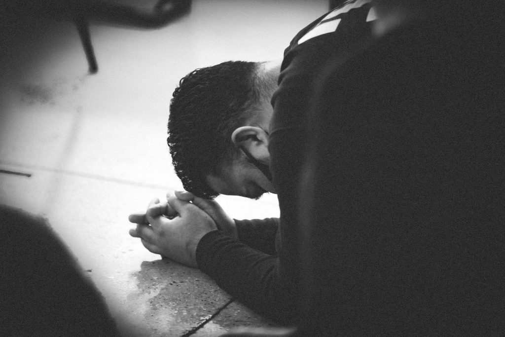 An image of someone on their knees praying. Living lives of sacrifice before God, as Romans 12 talks about.